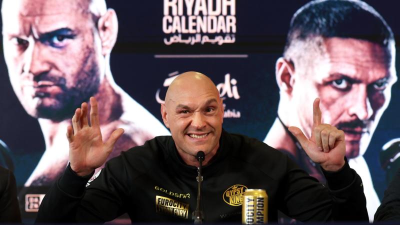 Tyson Fury holds up eight fingers at a news conference
