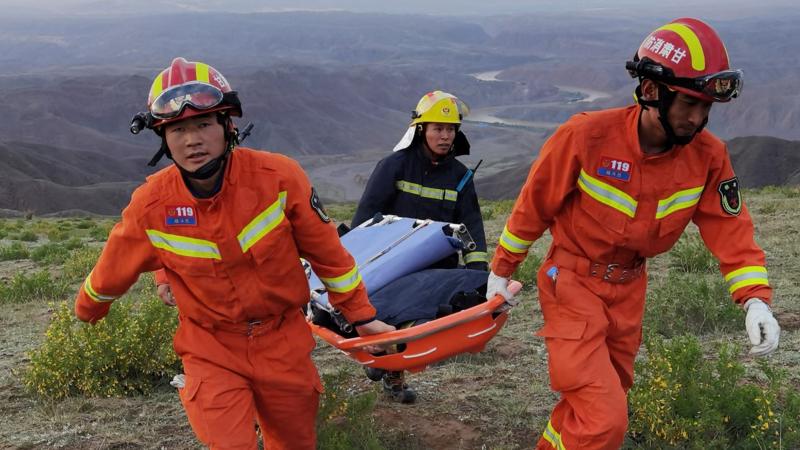This photo taken on May 22, 2021 shows rescuers carrying equipment as they search for runners who were competing in a 100-kilometre cross-country mountain race when extreme weather hit the area, leaving at least 20 dead, near the city of Baiyin in China's northwestern Gansu province