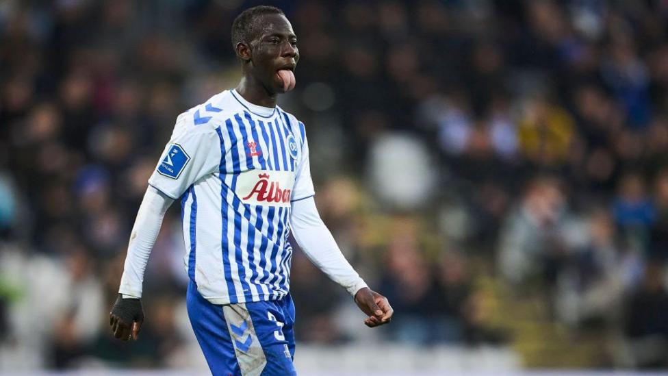  Yankuba Minteh, a Gambian professional footballer who plays as a forward for Danish Superliga club AaB, is playing soccer for Brighton.