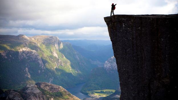 A hiker revels on top of Preikestolen in Norway (Credit: Credit: Anton Sokolov/iStock)