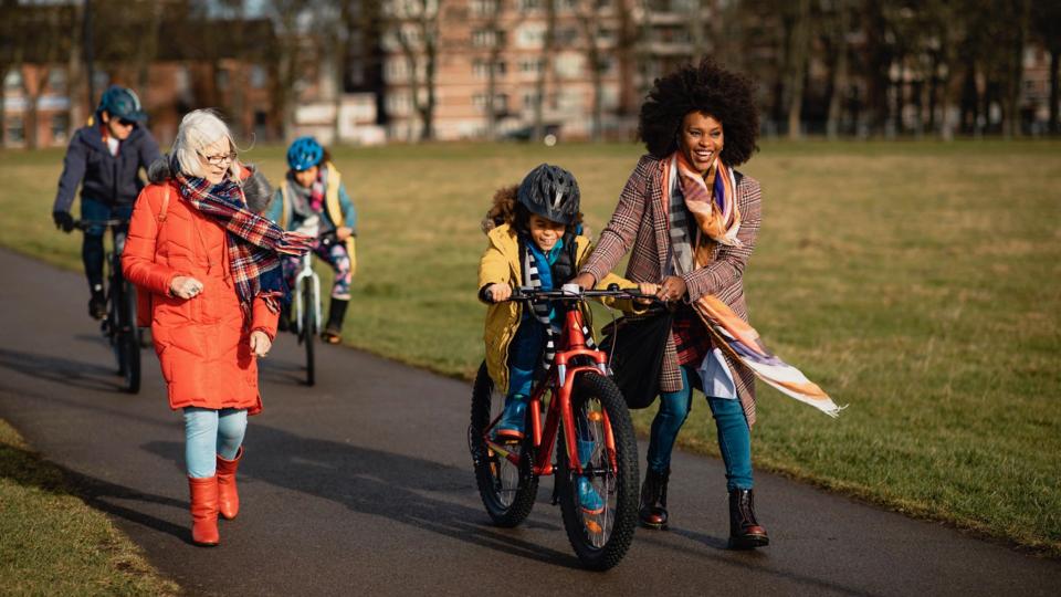 Boy cycling through a park with his family. Boy cycling through a park with his family.