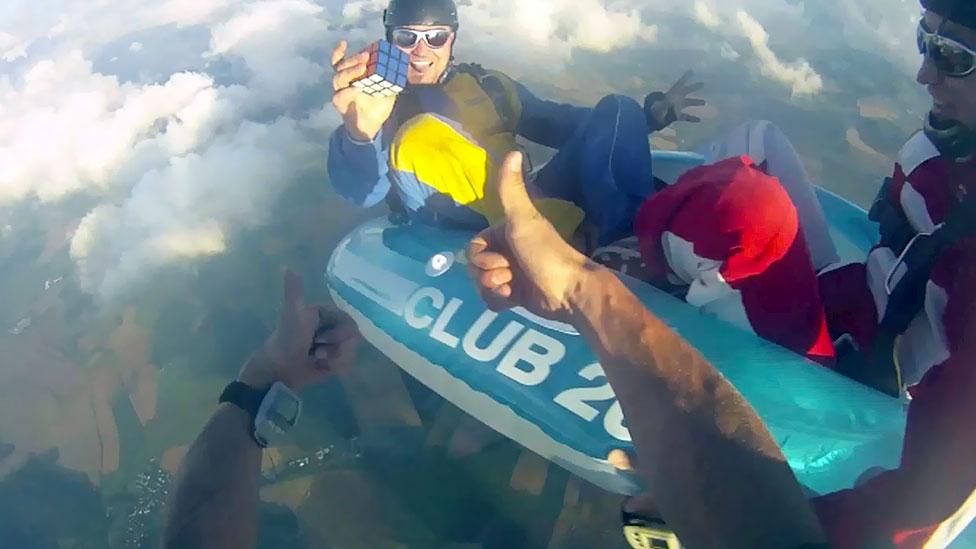 Cube enthusiasts try to solve it in unexpected places or manners – such as this person skydiving while working the puzzle. (Alamy) Cube enthusiasts try to solve it in unexpected places or manners – such as this person skydiving while working the puzzle. (Alamy)