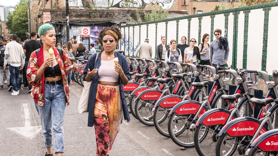 Women stroll in Shoreditch past the city’s shared bicycles, a scheme that launched in 2010 (Credit: Nicola Ferrari/Alamy) Women stroll in Shoreditch past the city’s shared bicycles, a scheme that launched in 2010 (Credit: Nicola Ferrari/Alamy)