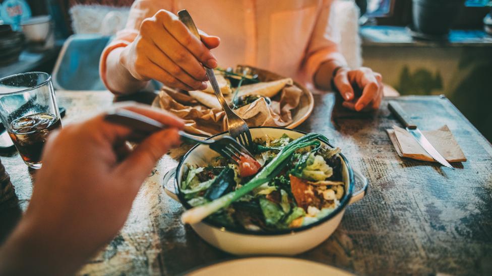 When you eat in company, you might be tempted to order bigger dishes to share (Credit: Getty Images) When you eat in company, you might be tempted to order bigger dishes to share (Credit: Getty Images)