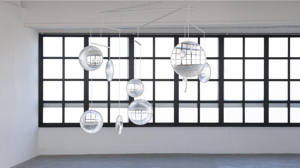 The kinetic piece, Focus, by architect Yuji Okitsu comprises clear glass lenses suspended in front of a window that refract light around the room The kinetic piece, Focus, by architect Yuji Okitsu comprises clear glass lenses suspended in front of a window that refract light around the room