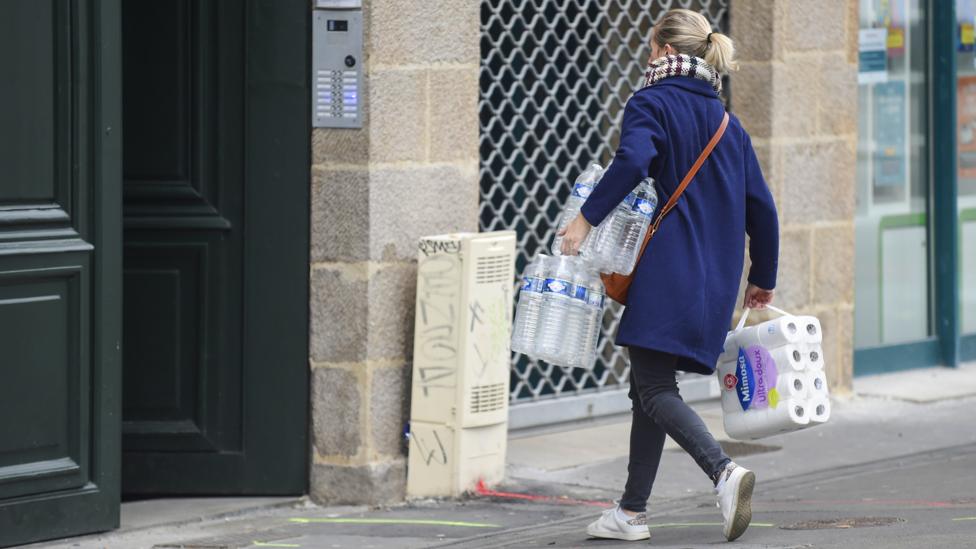 Woman carrying toilet rolls and bottled water back to her home (Credit: Getty Images)