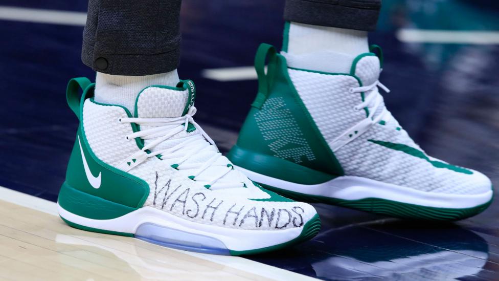 A basketball player's shoe with "WASH HANDS" scrawled on the side