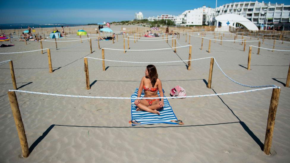 A woman in a bikini sits on the beach (Credit: Getty Images)